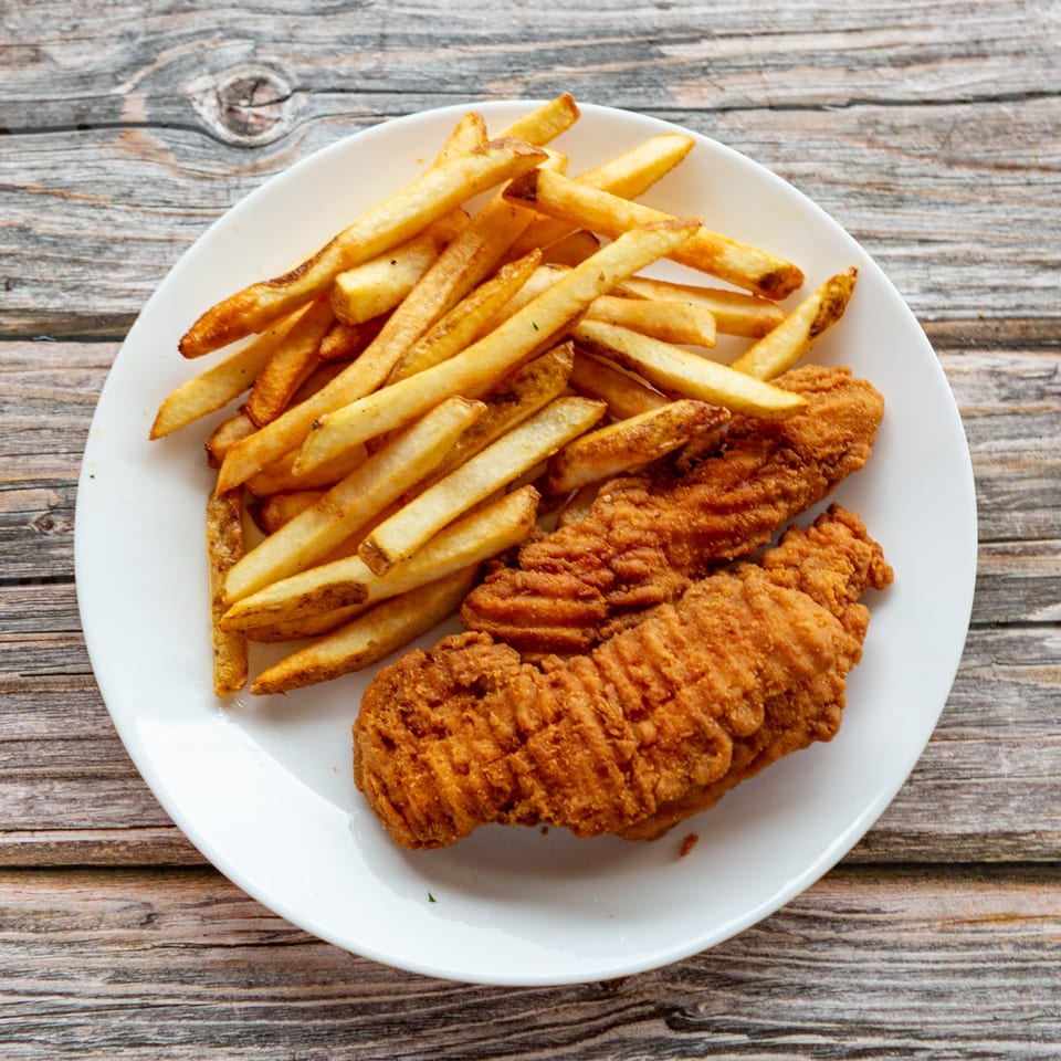 Crispy fried chicken tenders and golden french fries on a white plate, served at Greek Bites.